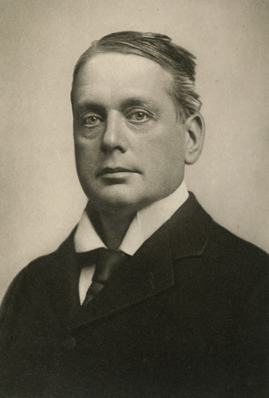 Black-and-white portrait of a middle-aged man in a suit with a high collar and tie, looking directly at the camera with a neutral expression.