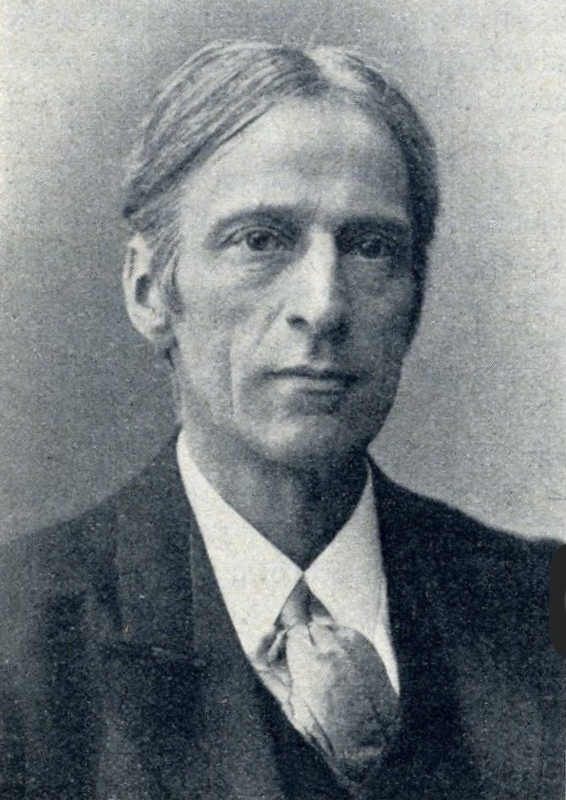 Black and white portrait of an older man with straight hair parted in the middle, wearing a suit, white shirt, and loose tie, looking seriously at the camera.